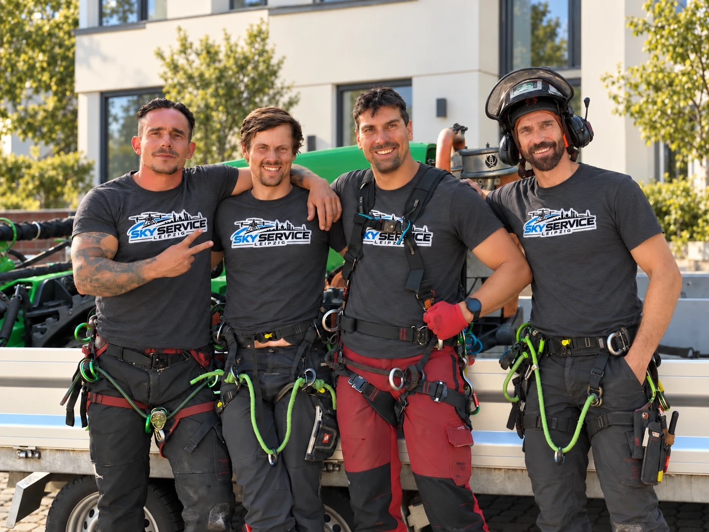 Vier Mitarbeiter von SkyService Leipzig in Firmen-T-Shirts vor einem Anhänger und einer Hausfassade